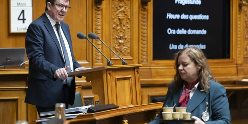 Bundesrat Albert Rösti spricht in der Fragestunde während Ratsweibelin Nathalie Radelfinger für die Verpflegung mit Kaffee sorgt. Foto: Peter Klaunzer (Keystone)