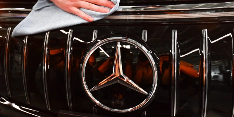 Trotz Klagen hat der Gewinn von Mercedes-Benz nicht an Glanz eingebüsst. epa10465195 Mercedes employee cleans the logo on a EQS car at the Mercedes-Benz plant in Sindelfingen. Foto: Anna Szilagy/EPA
