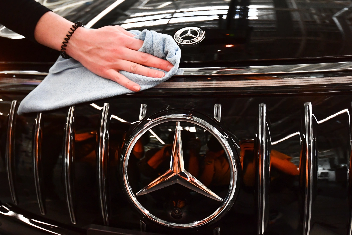 Trotz Klagen hat der Gewinn von Mercedes-Benz nicht an Glanz eingebüsst. epa10465195 Mercedes employee cleans the logo on a EQS car at the Mercedes-Benz plant in Sindelfingen. Foto: Anna Szilagy/EPA
